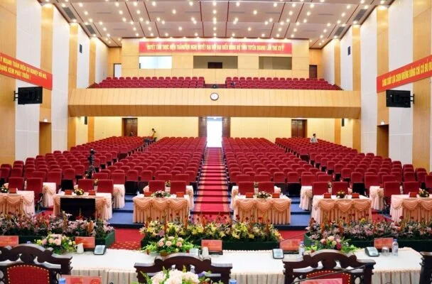 Hình ảnh minh họa không gian hội trường và trung tâm hội nghị được tích hợp hệ sinh thái âm thanh số. Các thiết bị như micro hội nghị, hệ thống loa biểu diễn, màn hình, camera, thiết bị livestream và phiên dịch được liên kết đồng bộ trên một nền tảng. Hệ thống thể hiện khả năng chuyển đổi linh hoạt giữa các chế độ vận hành thông qua các preset được lập trình sẵn.